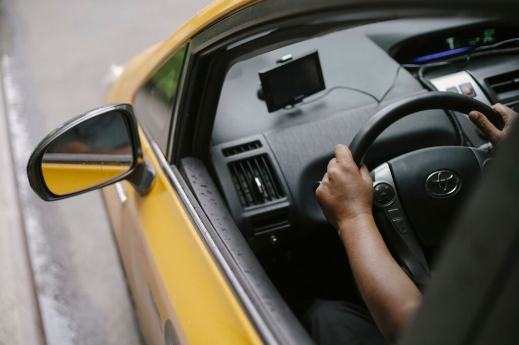 A driver at the wheel of a car, seen from the rear seats