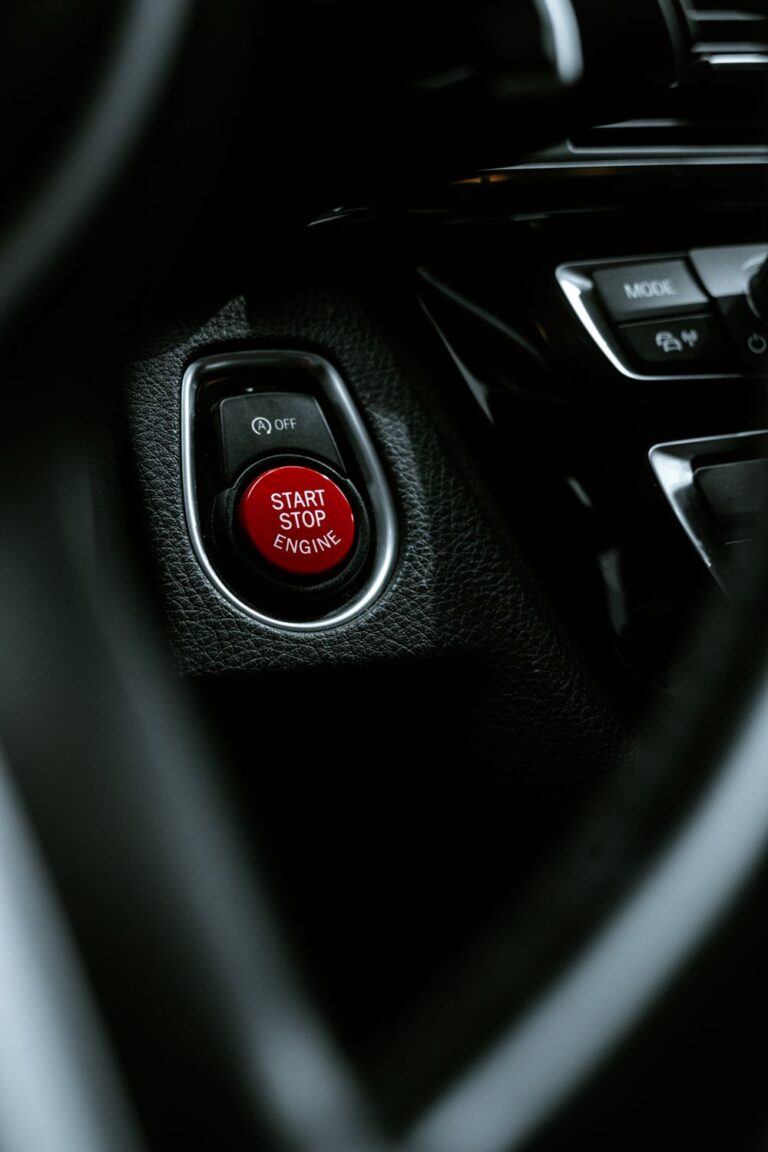 Close-up of a red engine start button on a dark car interior