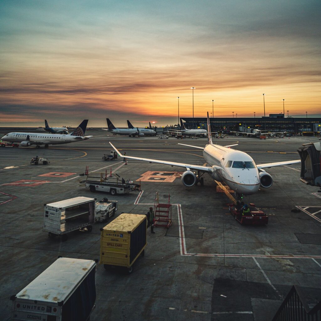 An aircraft parked at an airport gate at sunset