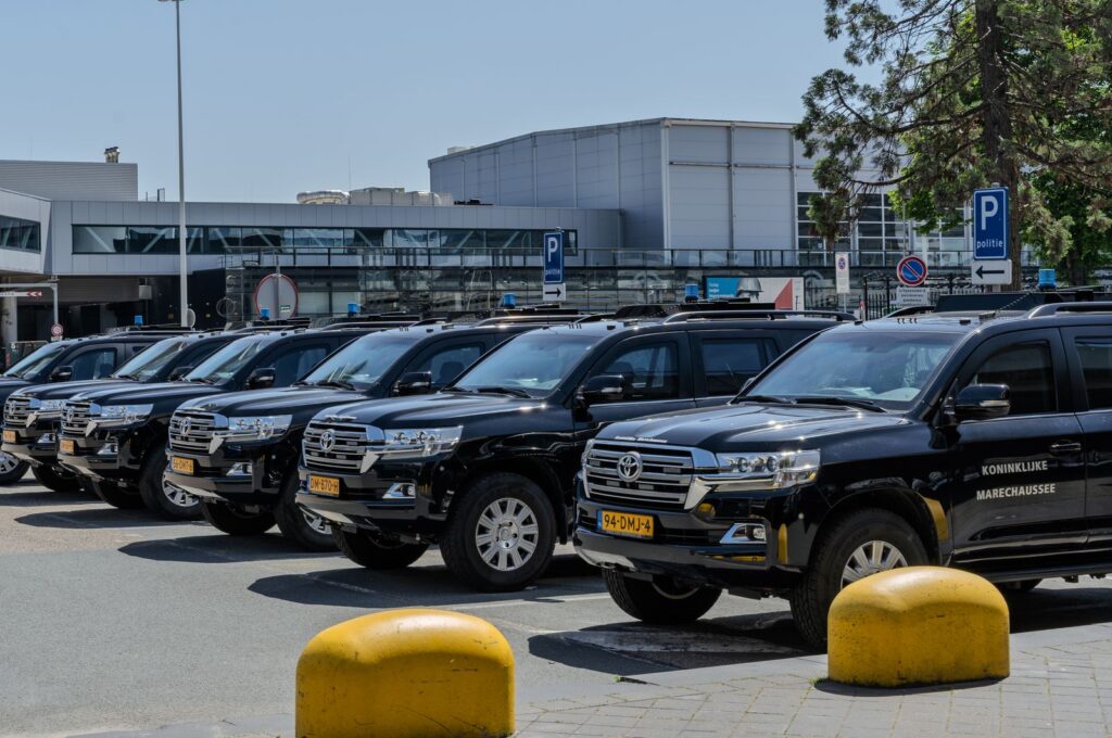 A line of dark vehicles waiting in an airport pickup area