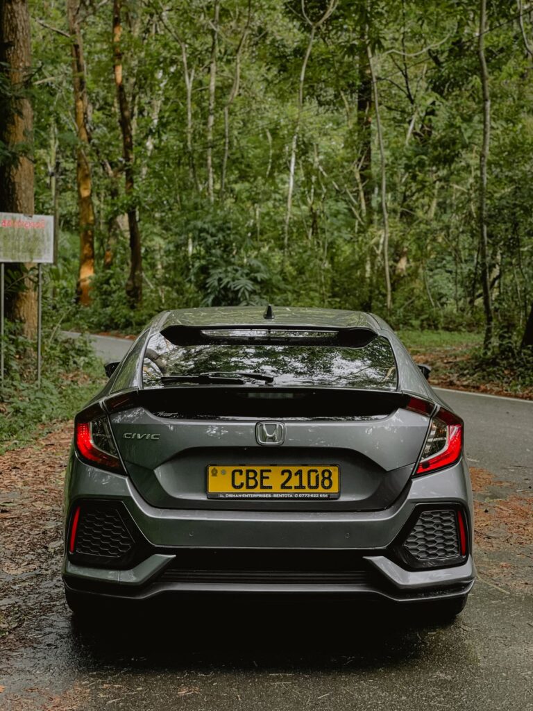 A hybrid sedan on a quiet road, with a Sri Lankan number plate